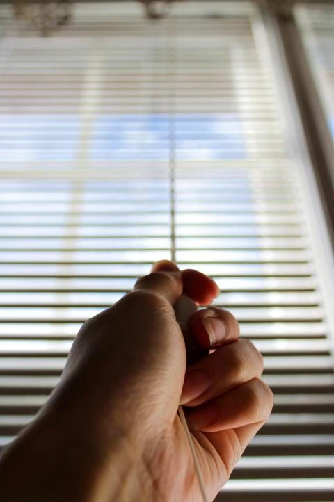 Mão ajustando o cordão de uma persiana